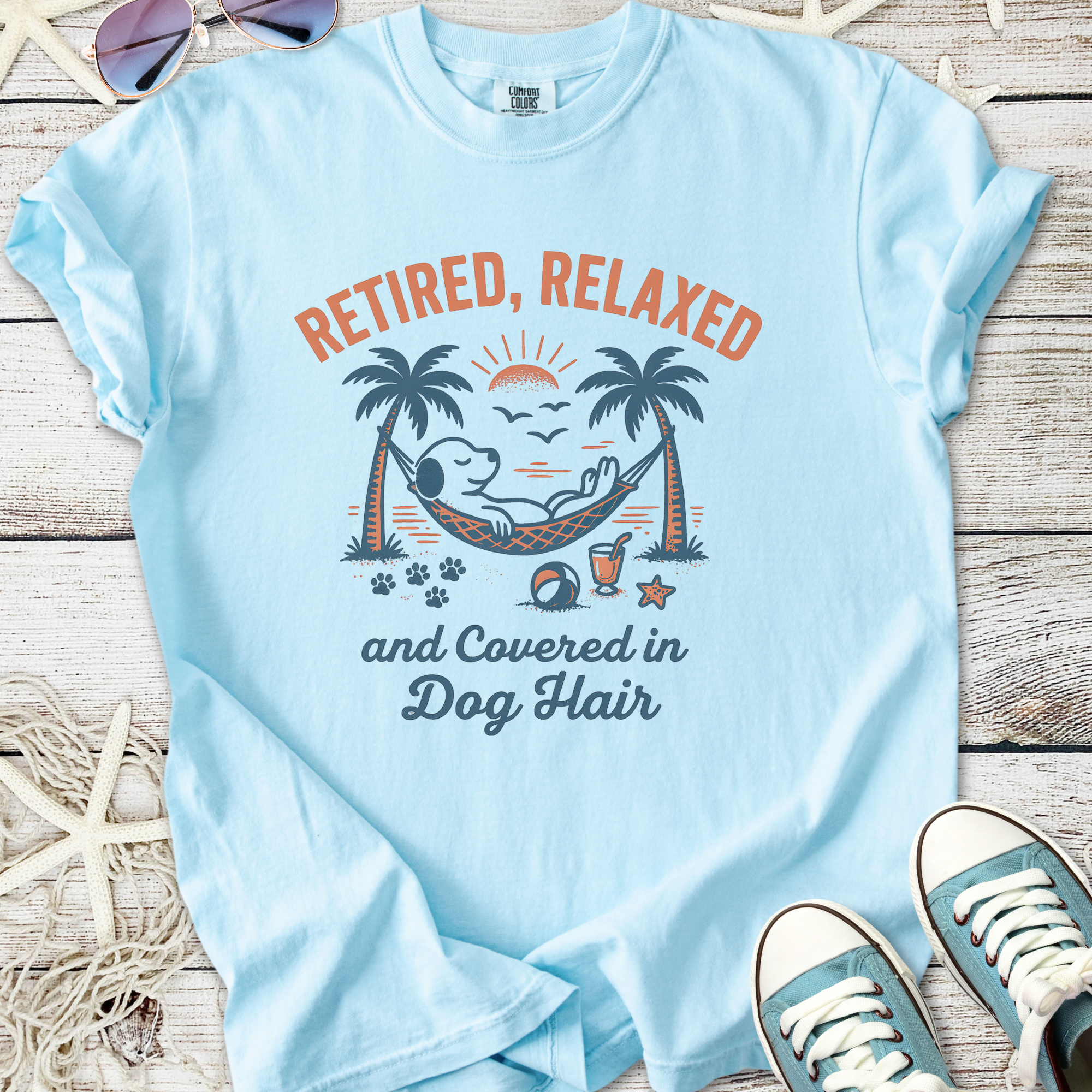 Light blue t-shirt featuring 'Retired, Relaxed, and Covered in Dog Hair' graphic with a hammock and dog design.