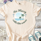 Beige t-shirt featuring 'His Mercy rolls like waves' graphic with palm trees and ocean design.