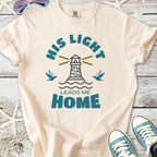 Beige cotton t-shirt with lighthouse design and text 'His Light Leads Me Home' for a casual and inspirational look.