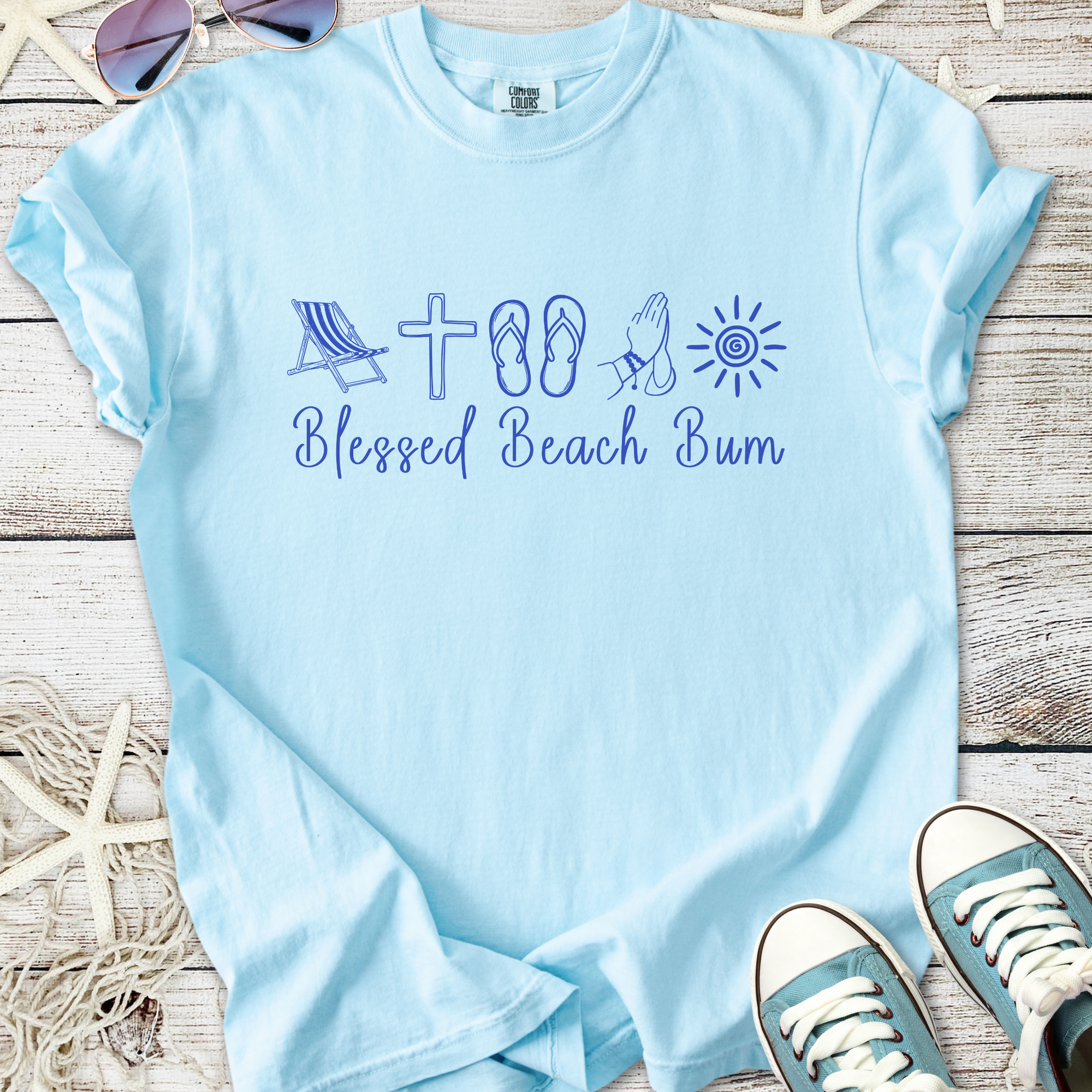Light blue t-shirt with 'Blessed Beach Bum' graphic, beach-themed icons, comfortable cotton material.