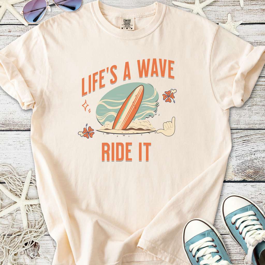 Cream cotton t-shirt with 'Life's a Wave, Ride It' graphic and surfboard design, perfect for beach lovers.
