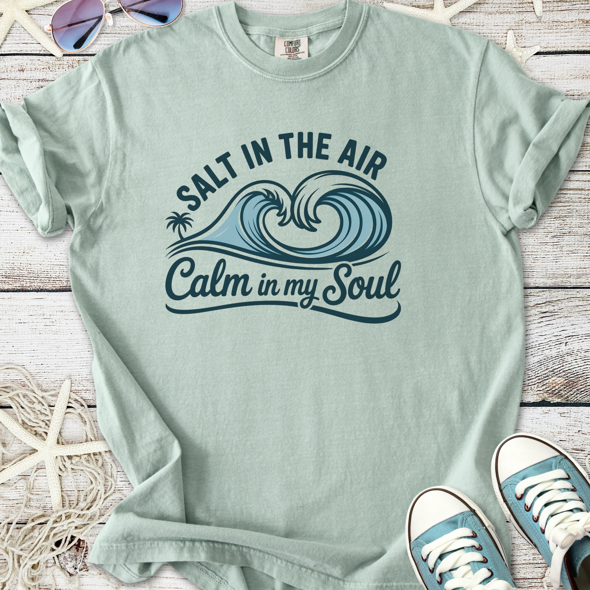 Light teal graphic tee featuring 'Salt in the Air, Calm in my Soul' design with wave and palm tree.