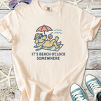 Cream graphic tee featuring a relaxed dog with sunglasses and the text 'It's Beach O'clock Somewhere'.