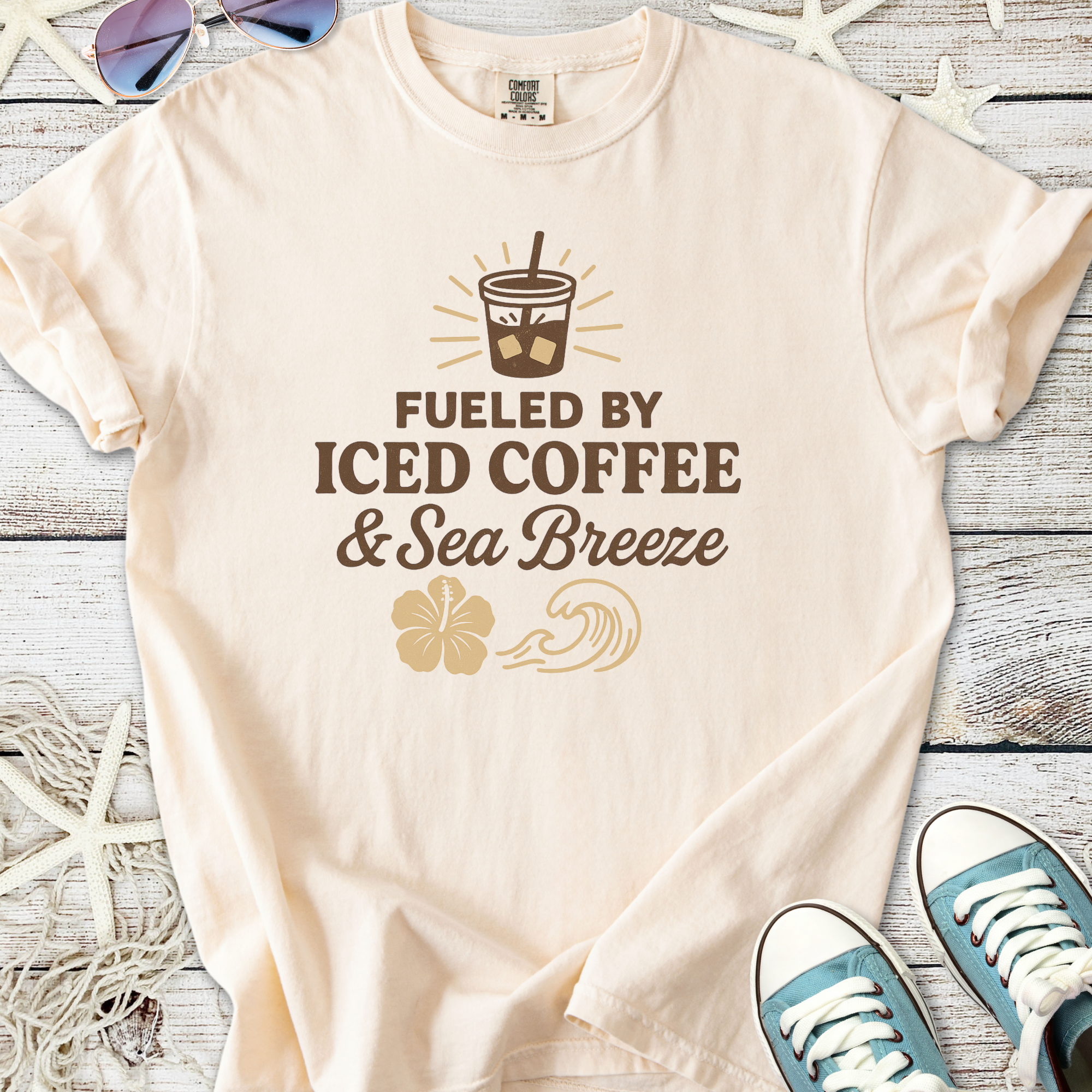 Light peach t-shirt with 'Fueled by Iced Coffee & Sea Breeze' graphic, soft cotton material.