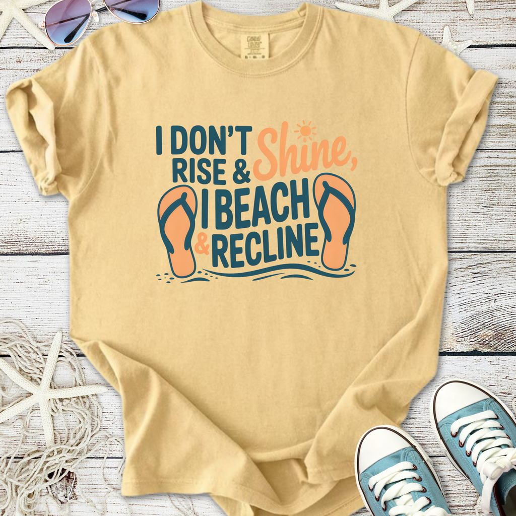 Light tan t-shirt with 'I don't rise & shine, I beach & recline' graphic, perfect for summer wear.