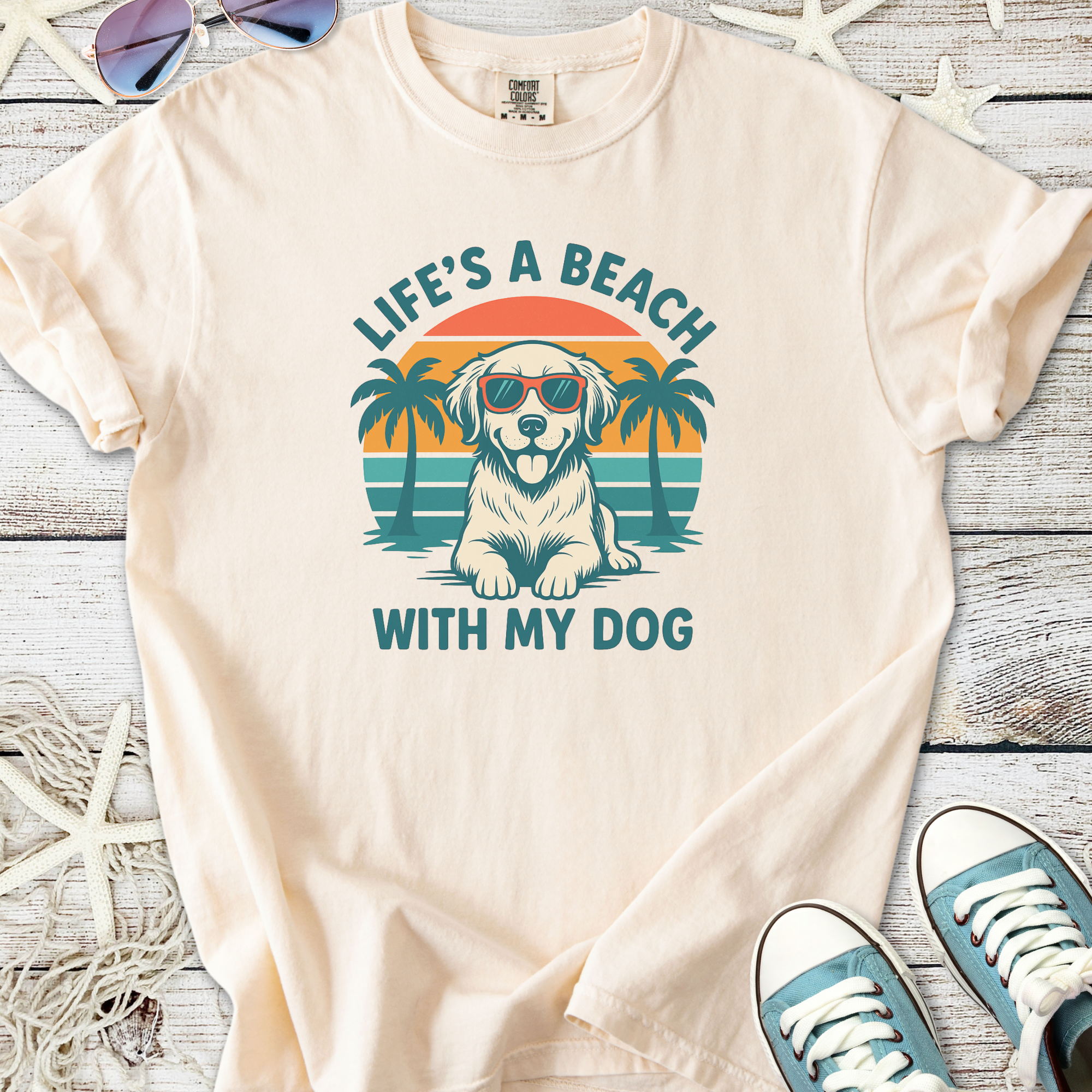 Cream t-shirt featuring a golden retriever wearing sunglasses and palm trees, perfect for dog lovers.