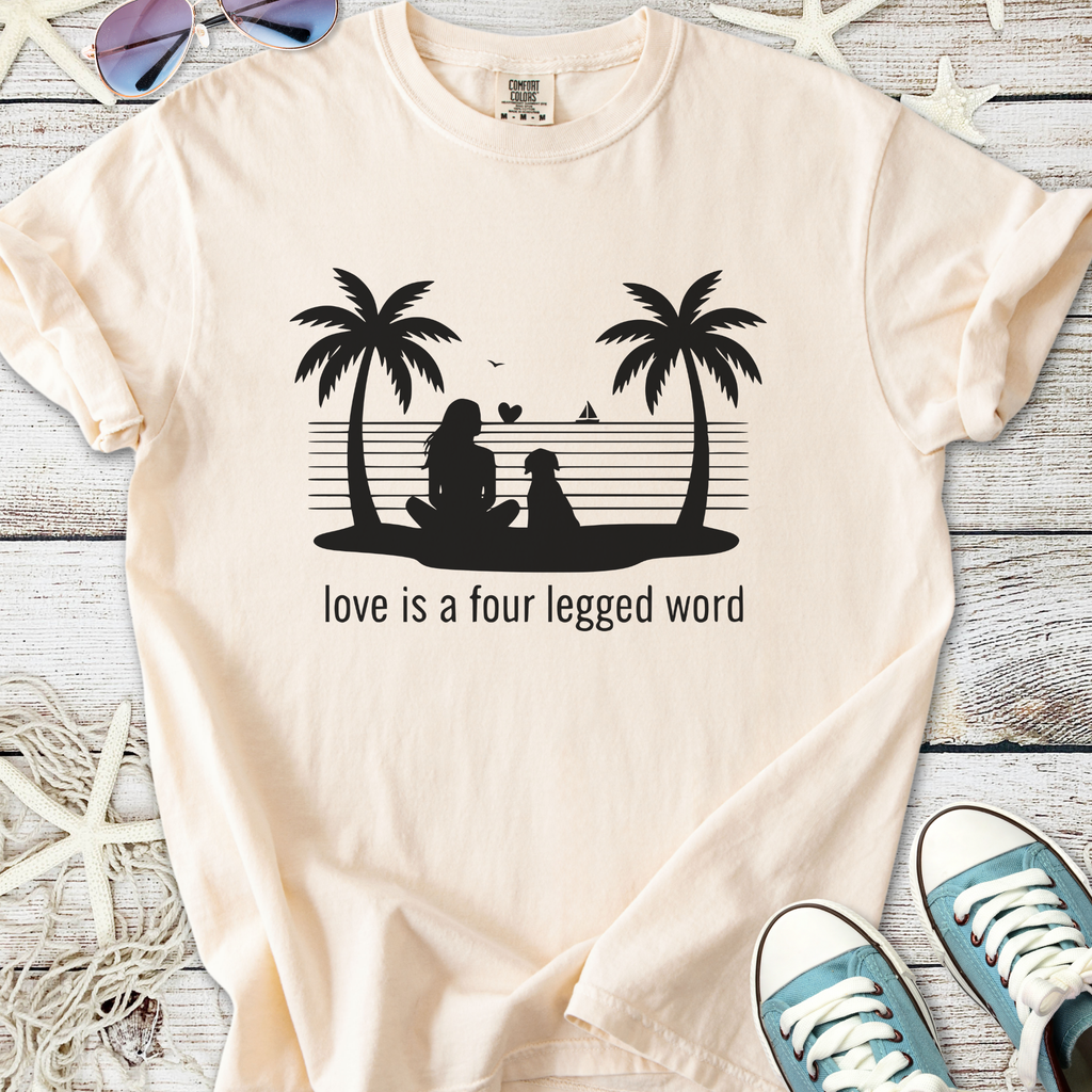 Beige t-shirt with silhouette of girl and dog, 'Love is a four legged word' text, beach theme.