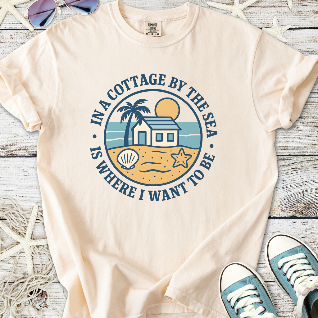 Cream graphic tee featuring beach scene with palm trees, house, and seashells, perfect for summer casual wear.