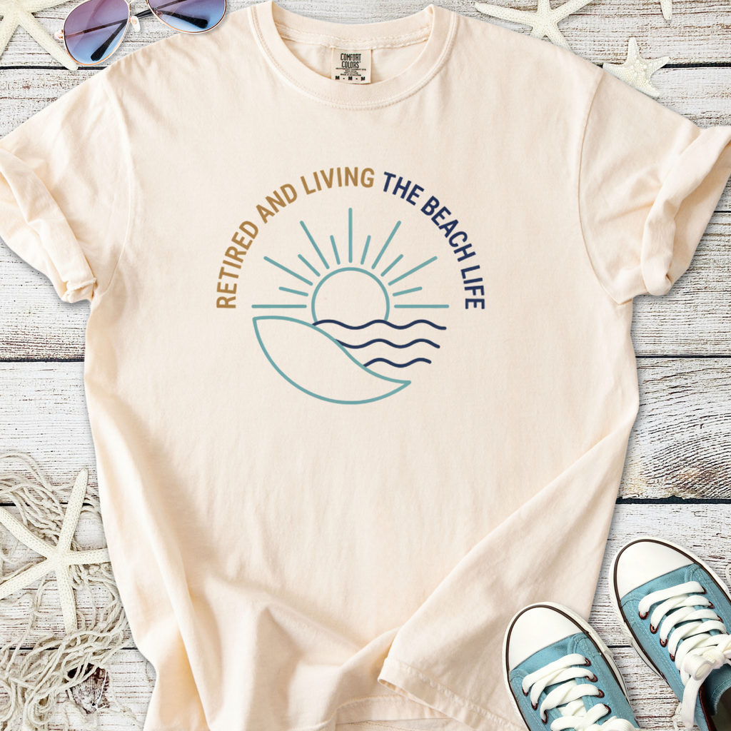 Cream cotton T-shirt with 'Retired and Living the Beach Life' graphic design and sun motif.