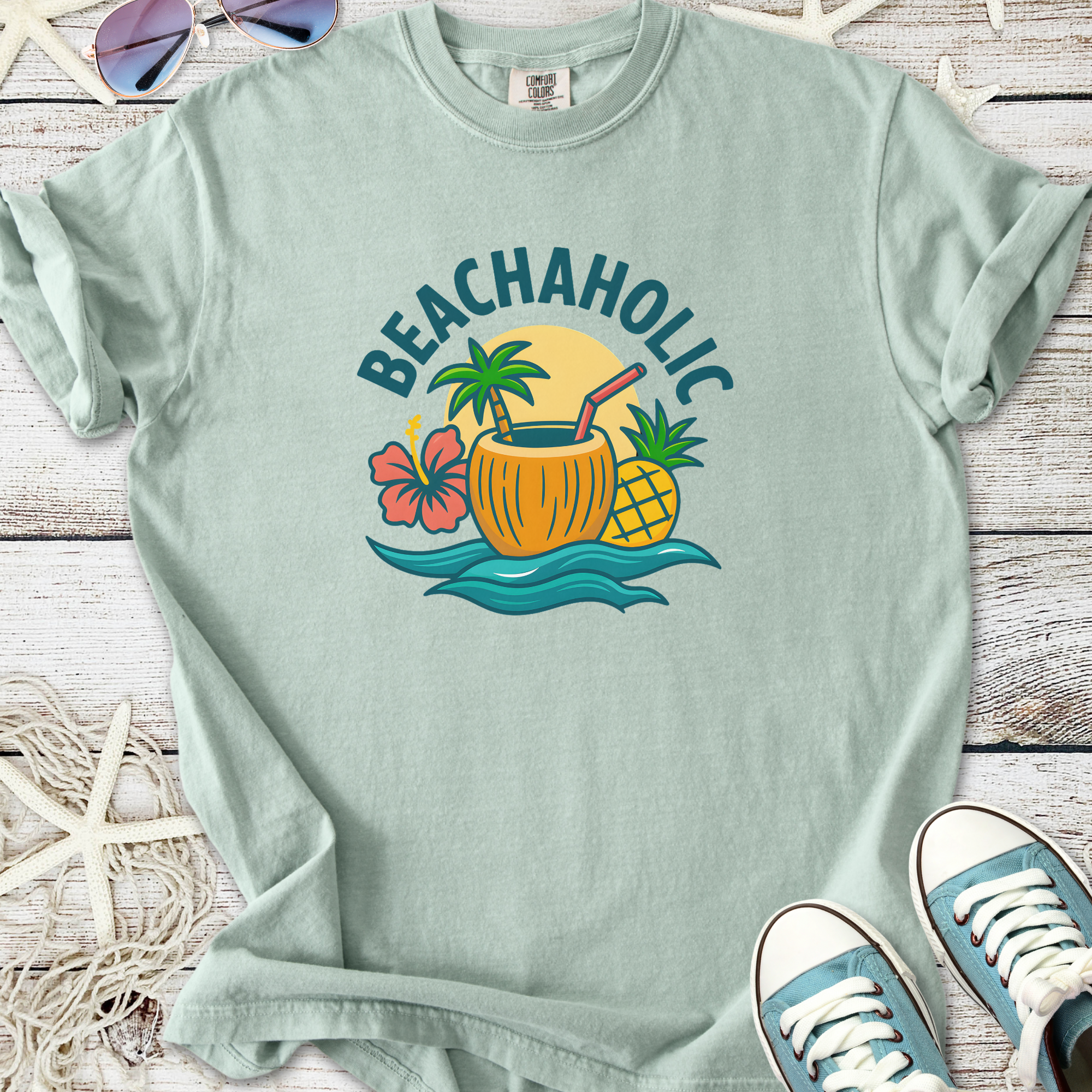 Mint green t-shirt with 'BEACHAHOLIC' graphic, featuring tropical drink and plants design.