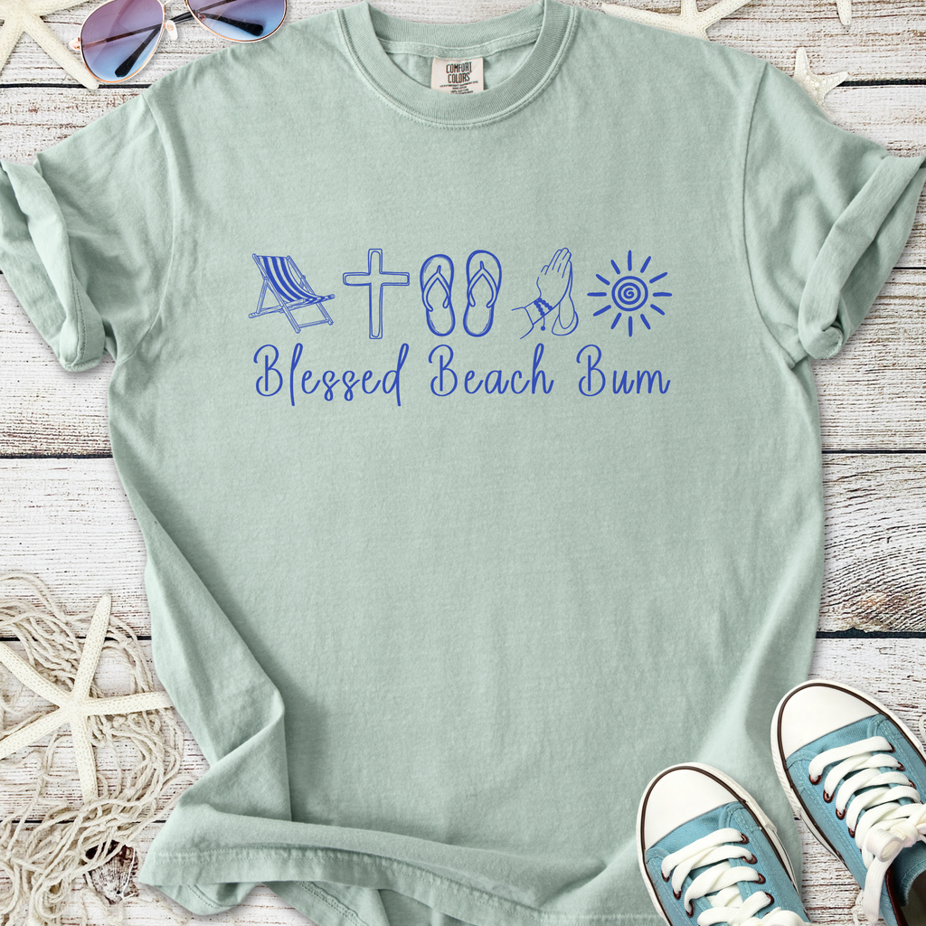 Light green t-shirt with 'Blessed Beach Bum' graphic, featuring beach icons and casual style.
