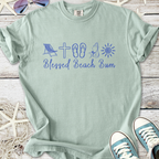 Light green t-shirt with 'Blessed Beach Bum' graphic, featuring beach icons and casual style.