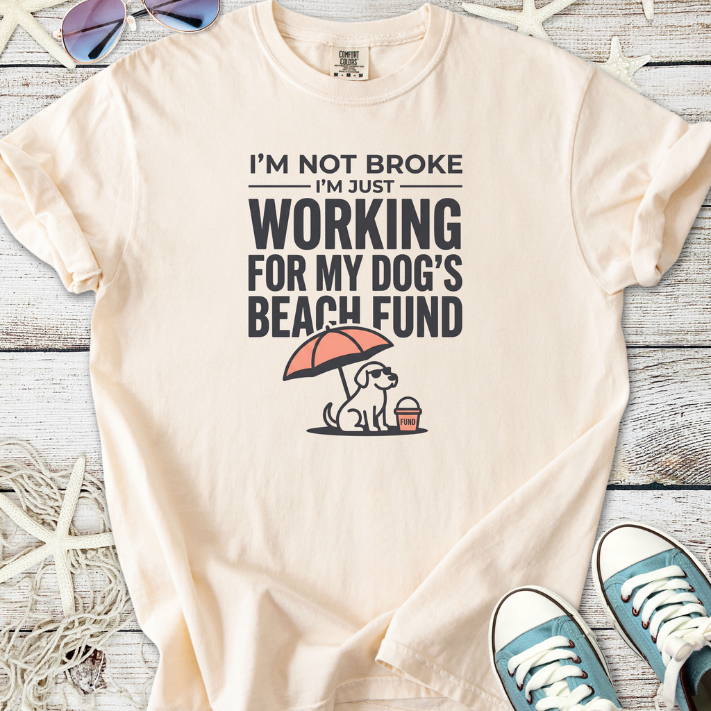 Cream graphic tee featuring a dog, beach umbrella, and text about dog fund, perfect for pet lovers.