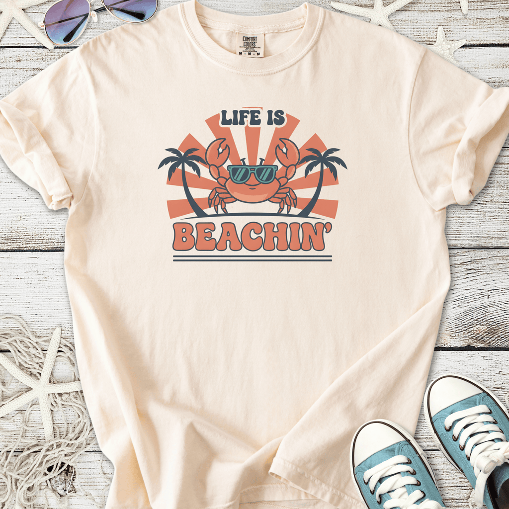 Light beige t-shirt featuring a fun crab graphic with sunglasses, text 'Life is Beachin', perfect for summer wear.