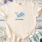 Light peach t-shirt with blue whale graphic, featuring the text 'oh whale...' Perfect for casual wear.
