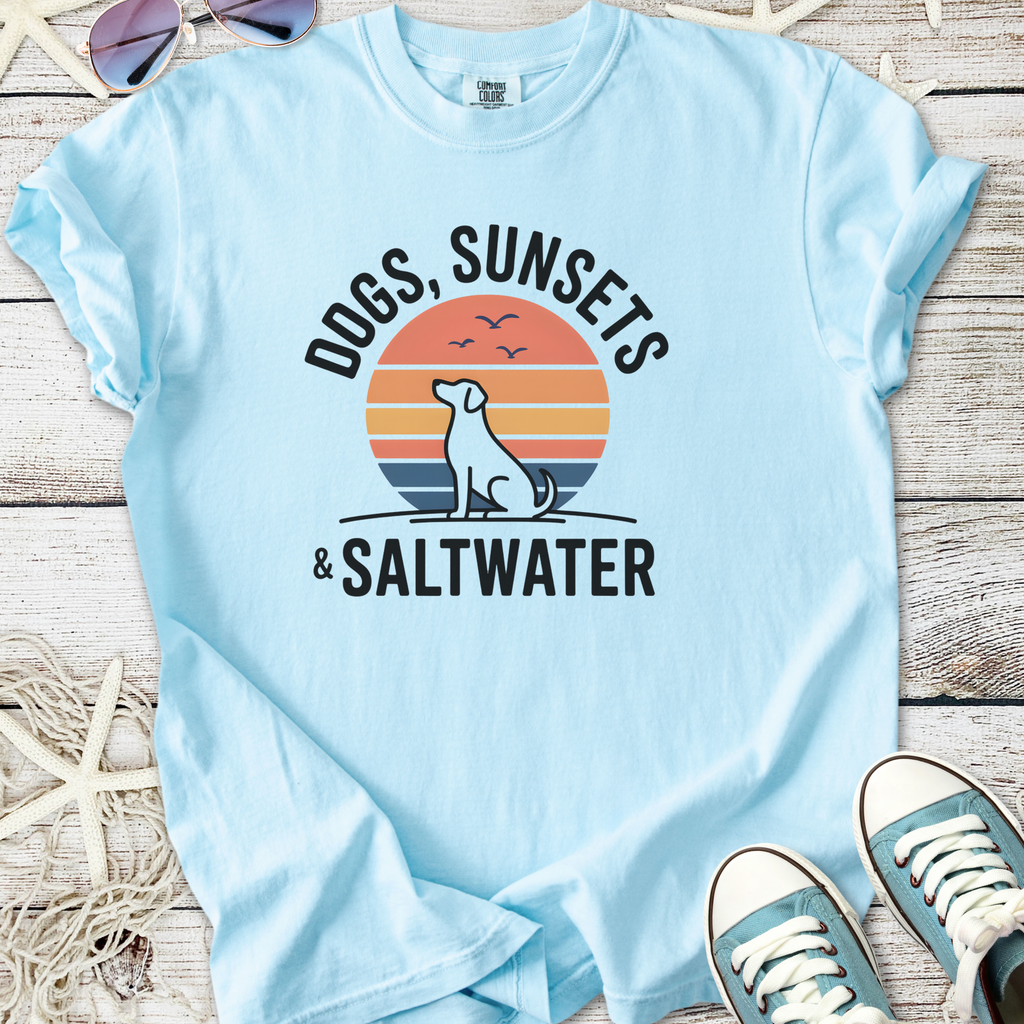 Light blue t-shirt featuring 'Dogs, Sunsets & Saltwater' graphic design and a silhouette of a dog.