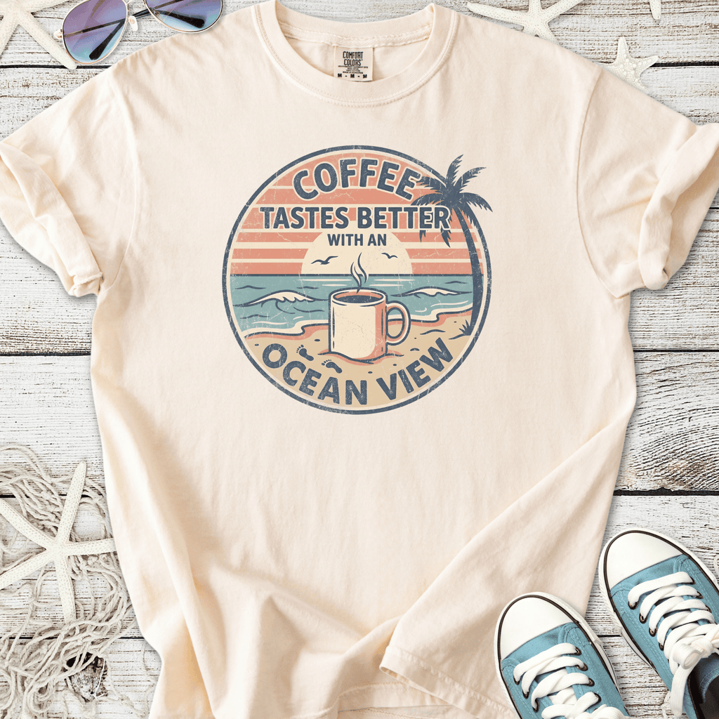 Beige t-shirt with ocean view coffee graphic, lightweight cotton, perfect for beach lovers.