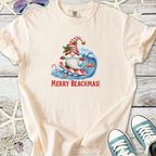 Cream t-shirt featuring a surfing Santa with 'Merry Beachmas!' print. Perfect for holiday beach celebrations.