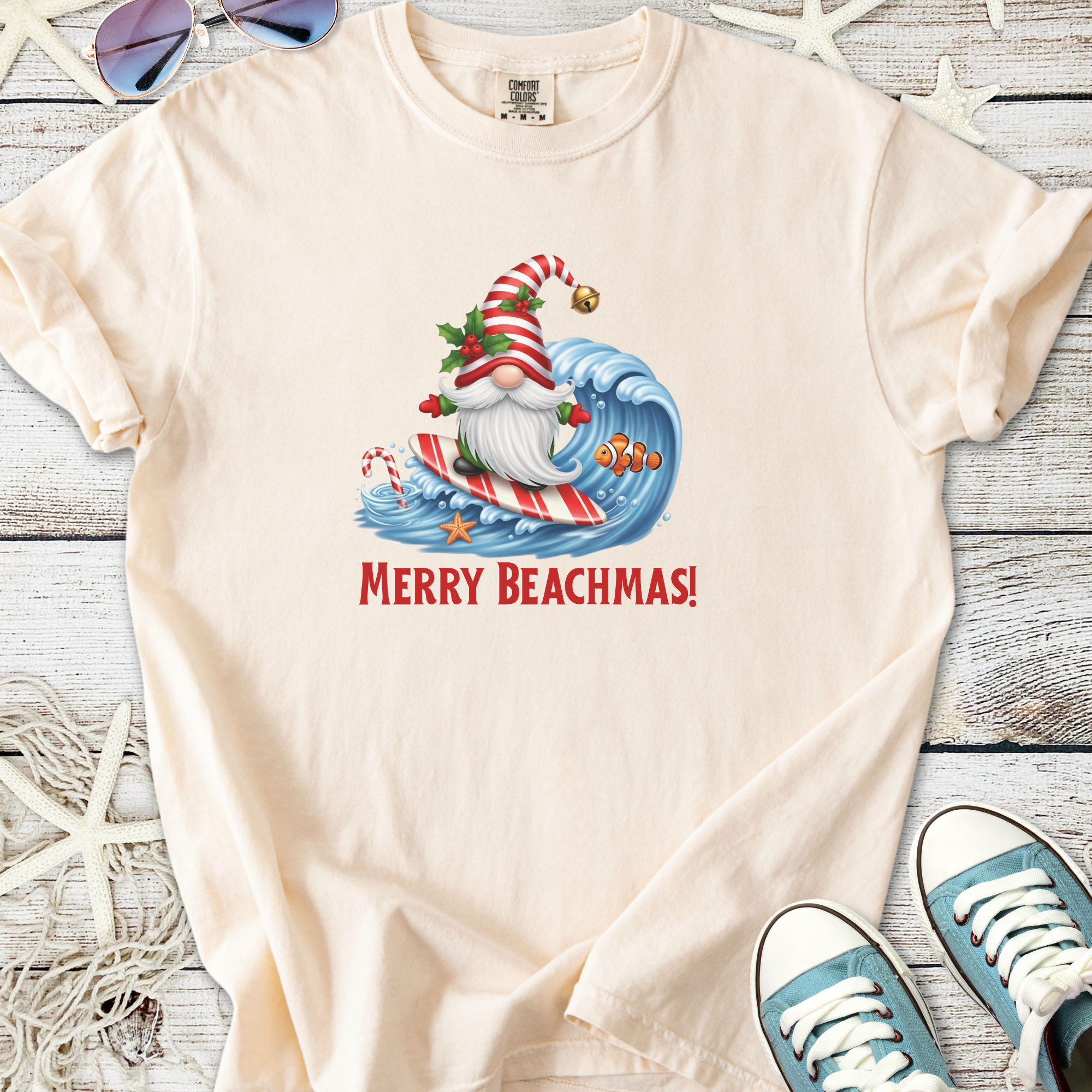 Cream t-shirt featuring a surfing Santa with 'Merry Beachmas!' print. Perfect for holiday beach celebrations.