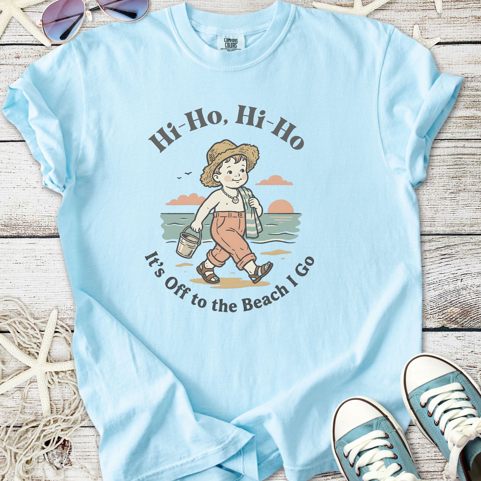 Light blue t-shirt featuring a vintage beach graphic with a child, perfect for summer outings.