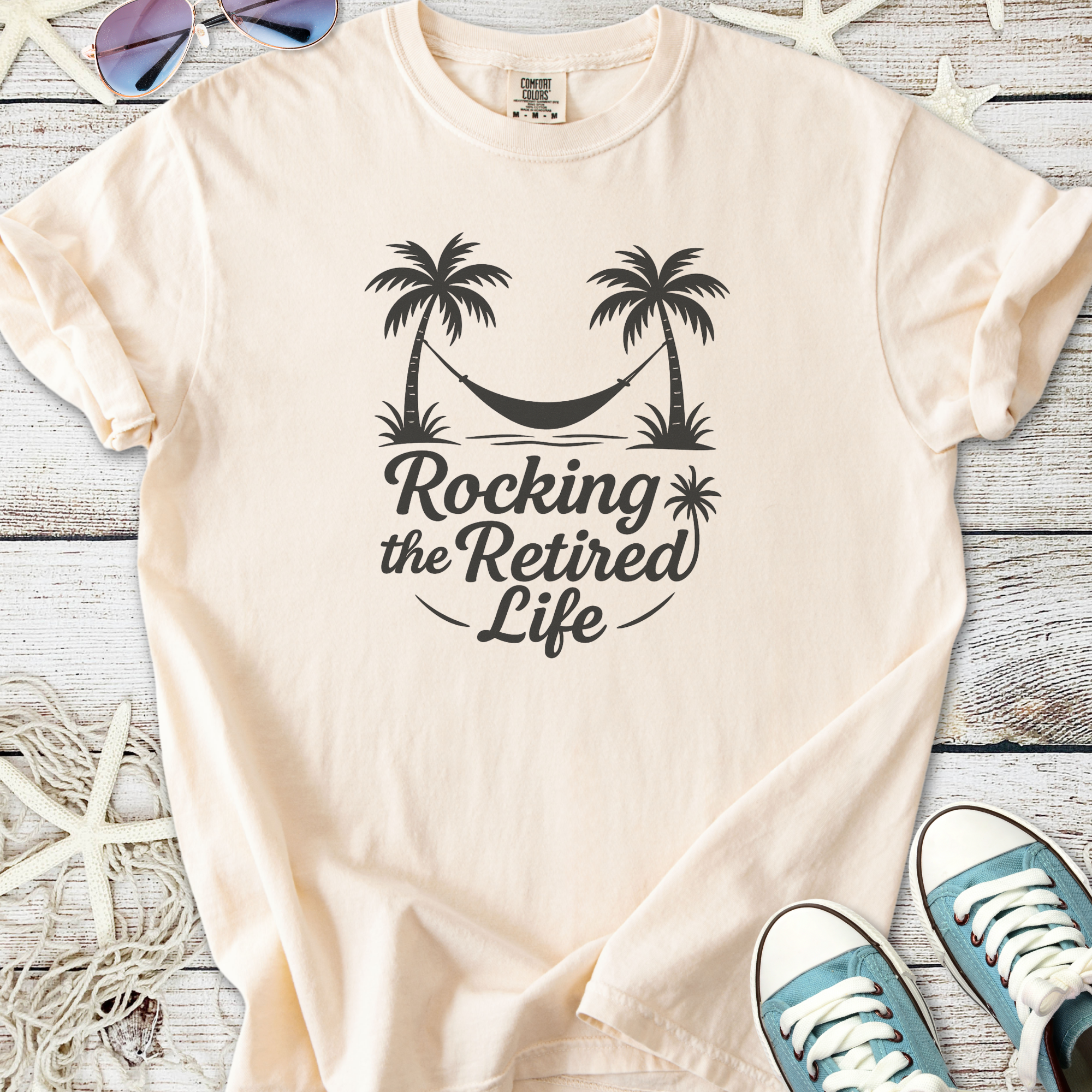 Cream cotton t-shirt featuring 'Rocking the Retired Life' design with palm trees and a hammock.