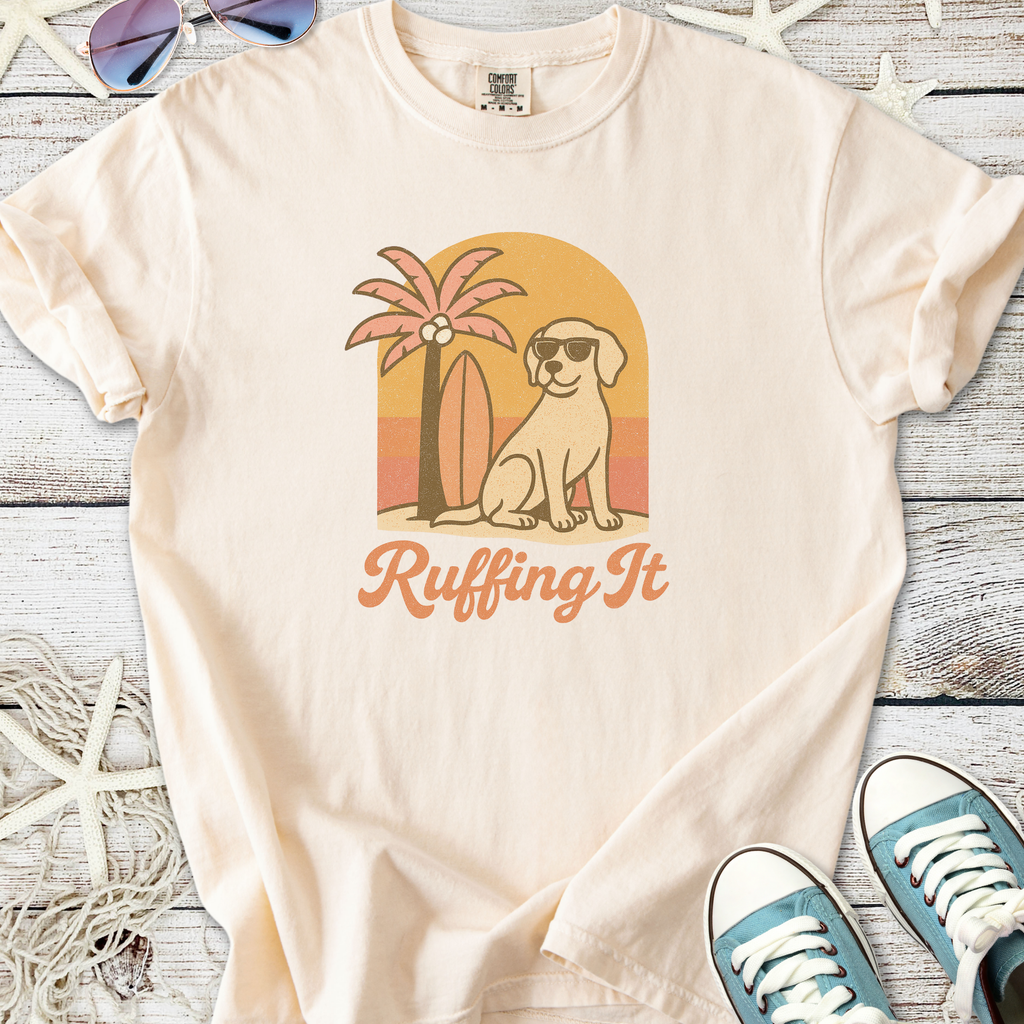 Cream graphic t-shirt featuring a dog, palm tree, and surfboard design with 'Ruffing It' text.