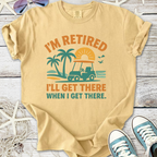 Beige retired graphic t-shirt featuring a golf cart, palm trees, and sunset design for casual wear.