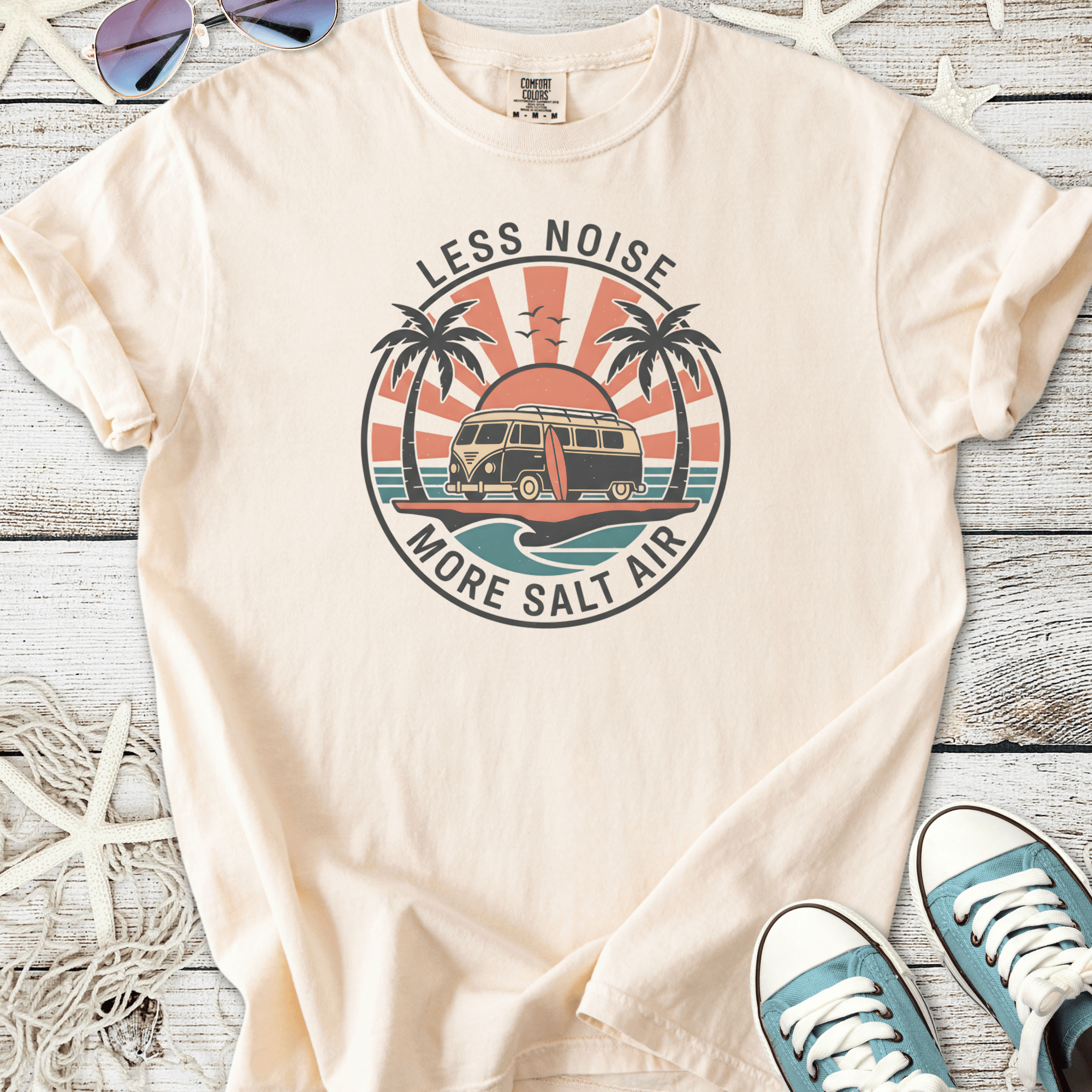 Cream t-shirt with 'Less Noise More Salt Air' graphic, featuring a surf van and palm trees.