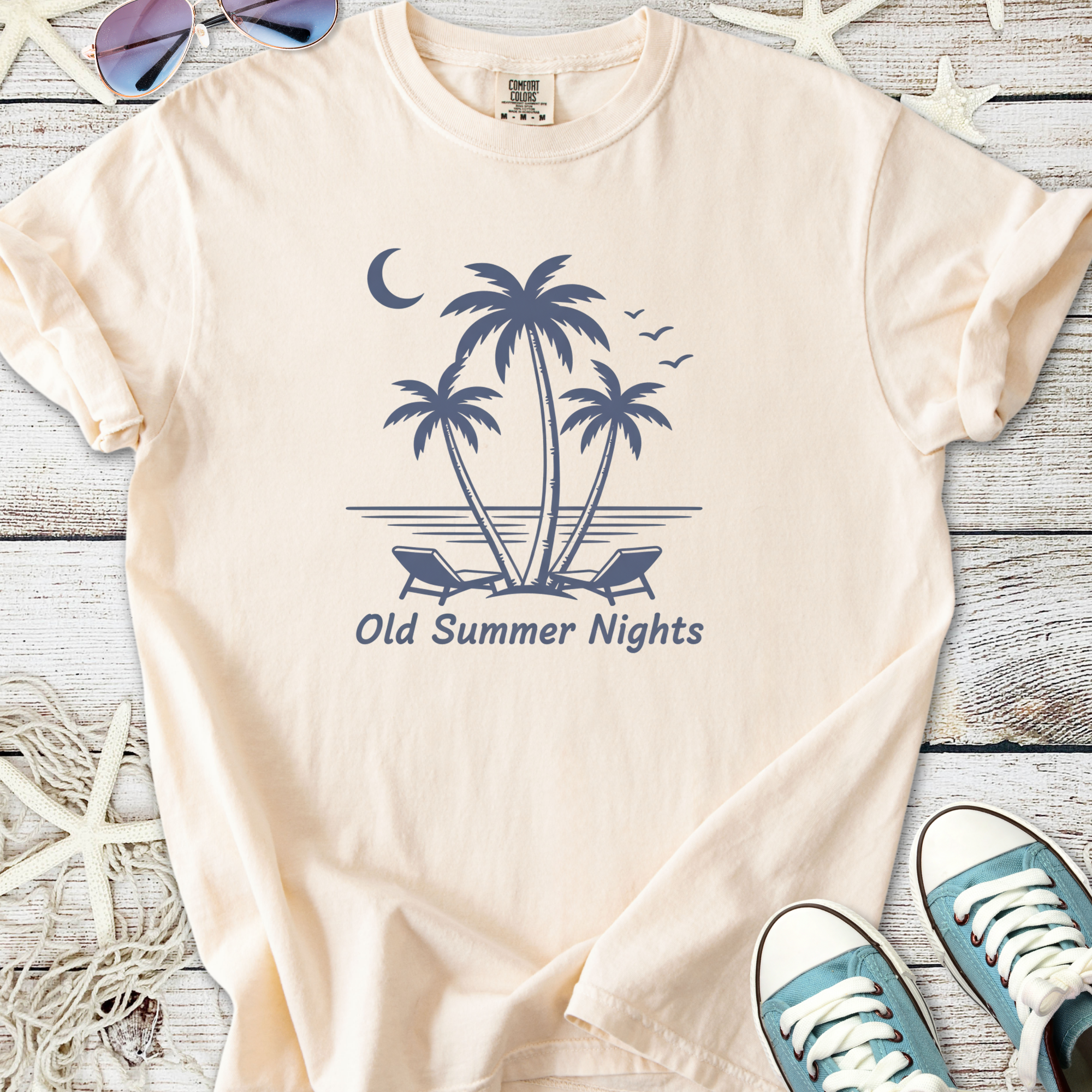 Cream t-shirt featuring a vintage summer night design with palm trees and lounge chairs.