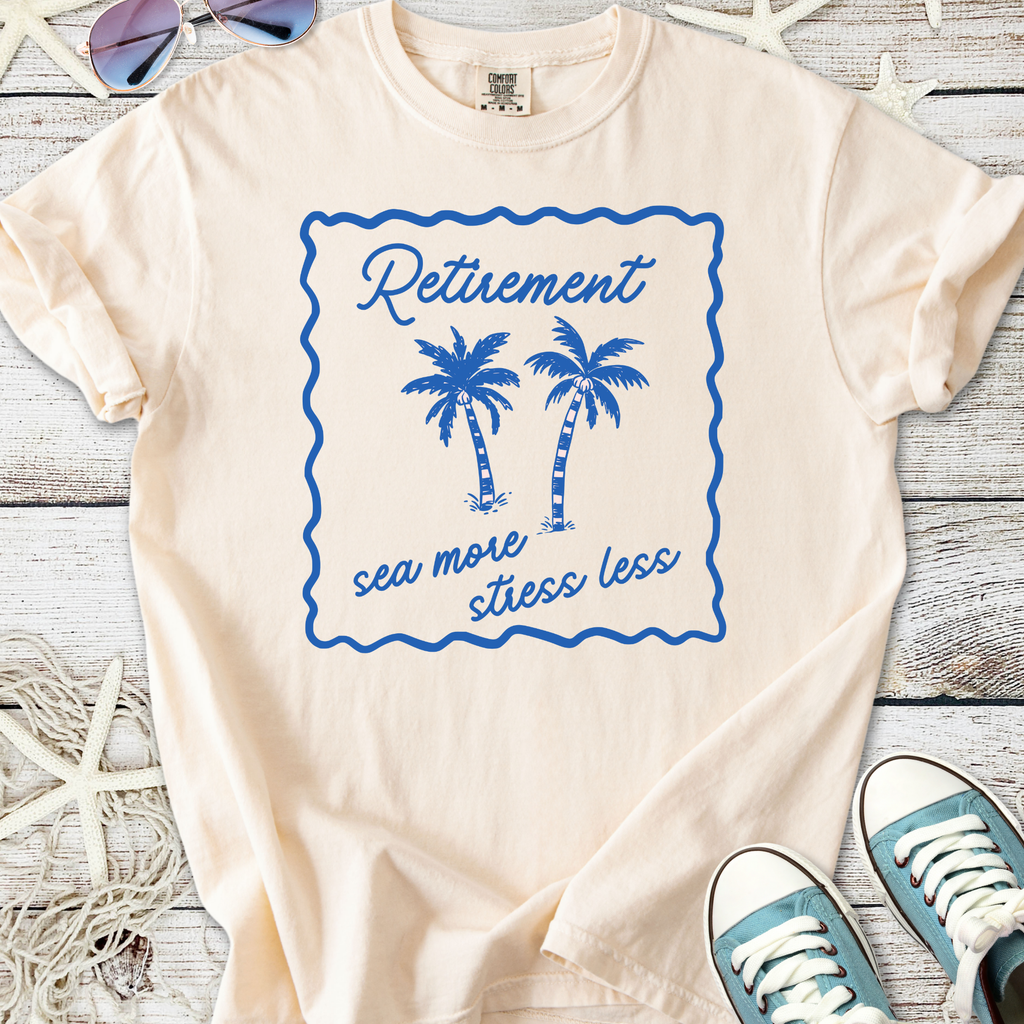Cream retirement t-shirt with blue palm tree graphic and 'sea more stress less' slogan.