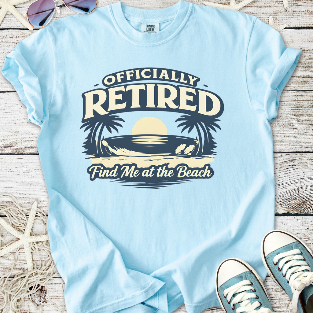 Light blue t-shirt with 'Officially Retired' graphic, beach theme, casual style for retirees.