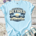 Light blue t-shirt with 'Officially Retired' graphic, beach theme, casual style for retirees.