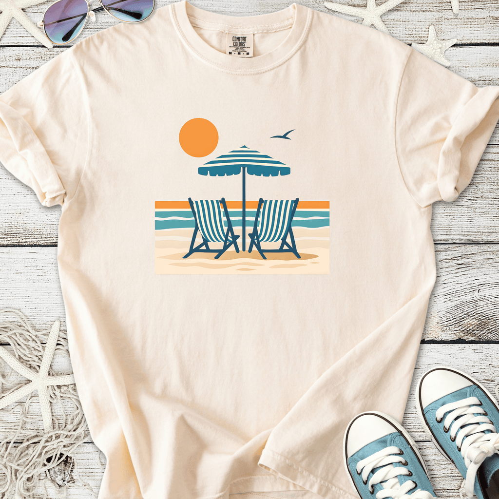Light beige t-shirt featuring beach chairs and an umbrella graphic, perfect for summer vibes.