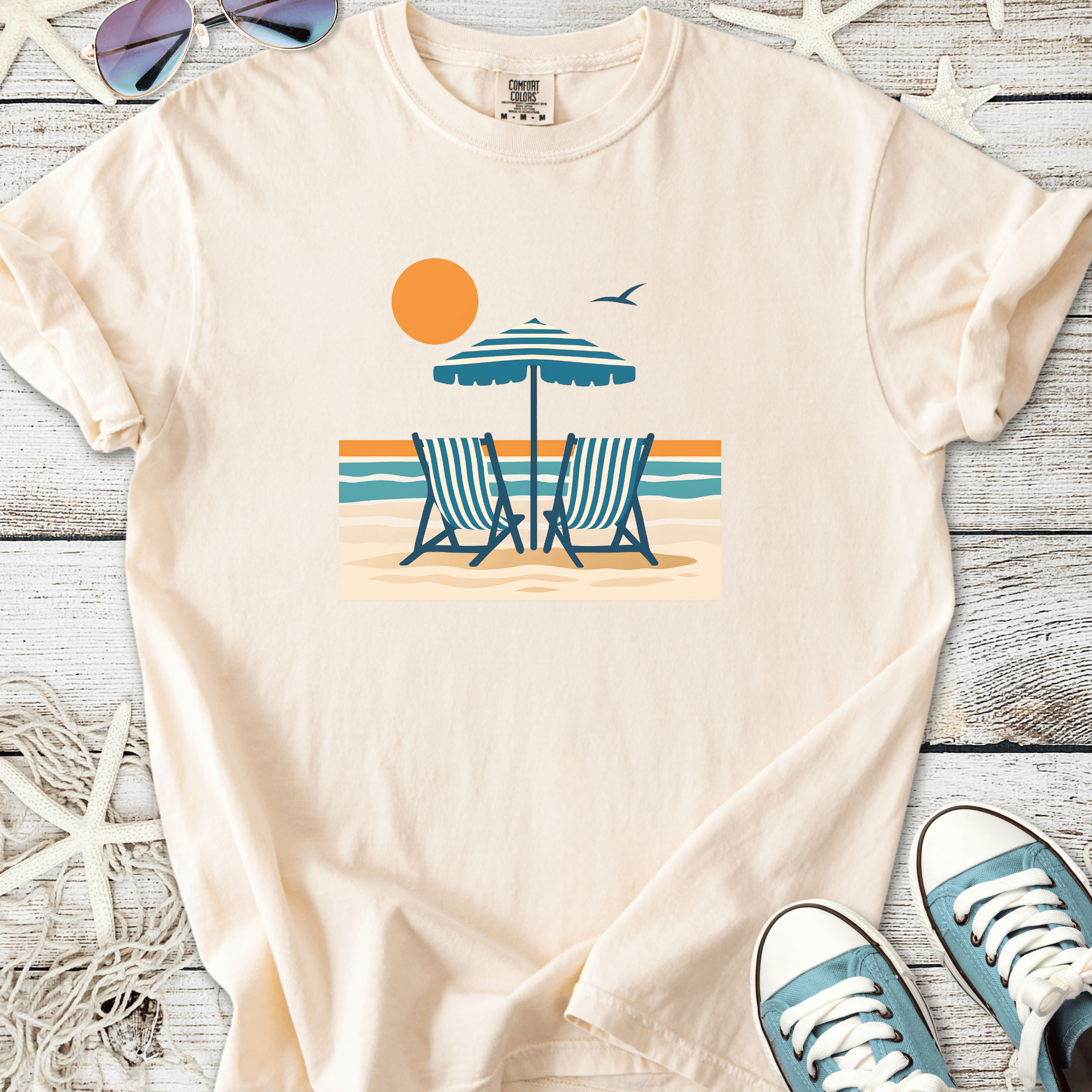 Light beige t-shirt featuring beach chairs and an umbrella graphic, perfect for summer vibes.