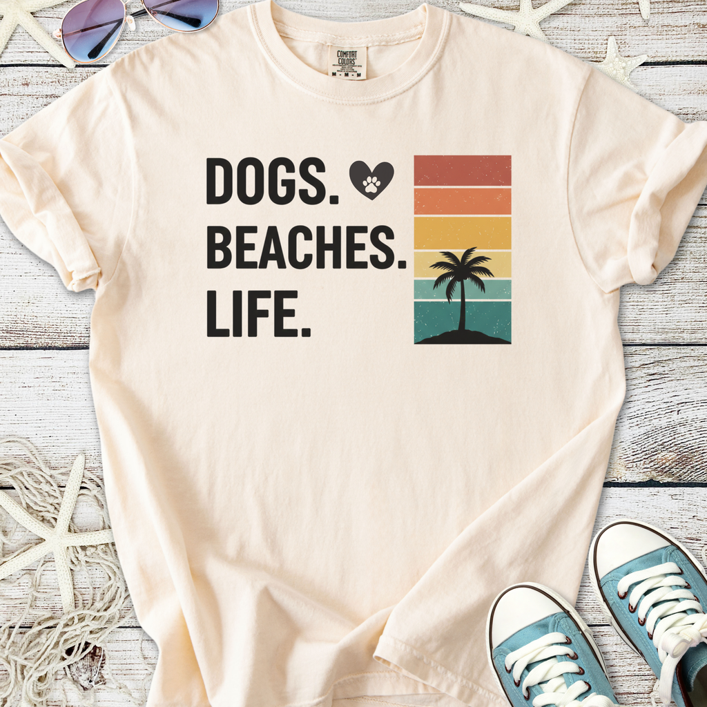 Cream t-shirt with 'Dogs. Beaches. Life.' graphic, featuring a palm tree and sunset colors, perfect for beach lovers.