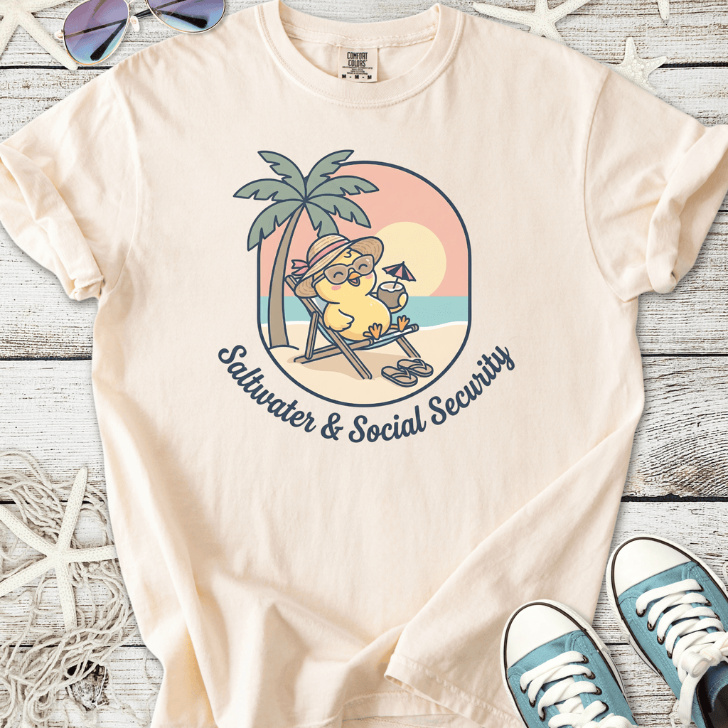 Beige cotton t-shirt featuring a cartoon character relaxing on a beach with the text 'Saltwater & Social Security'.