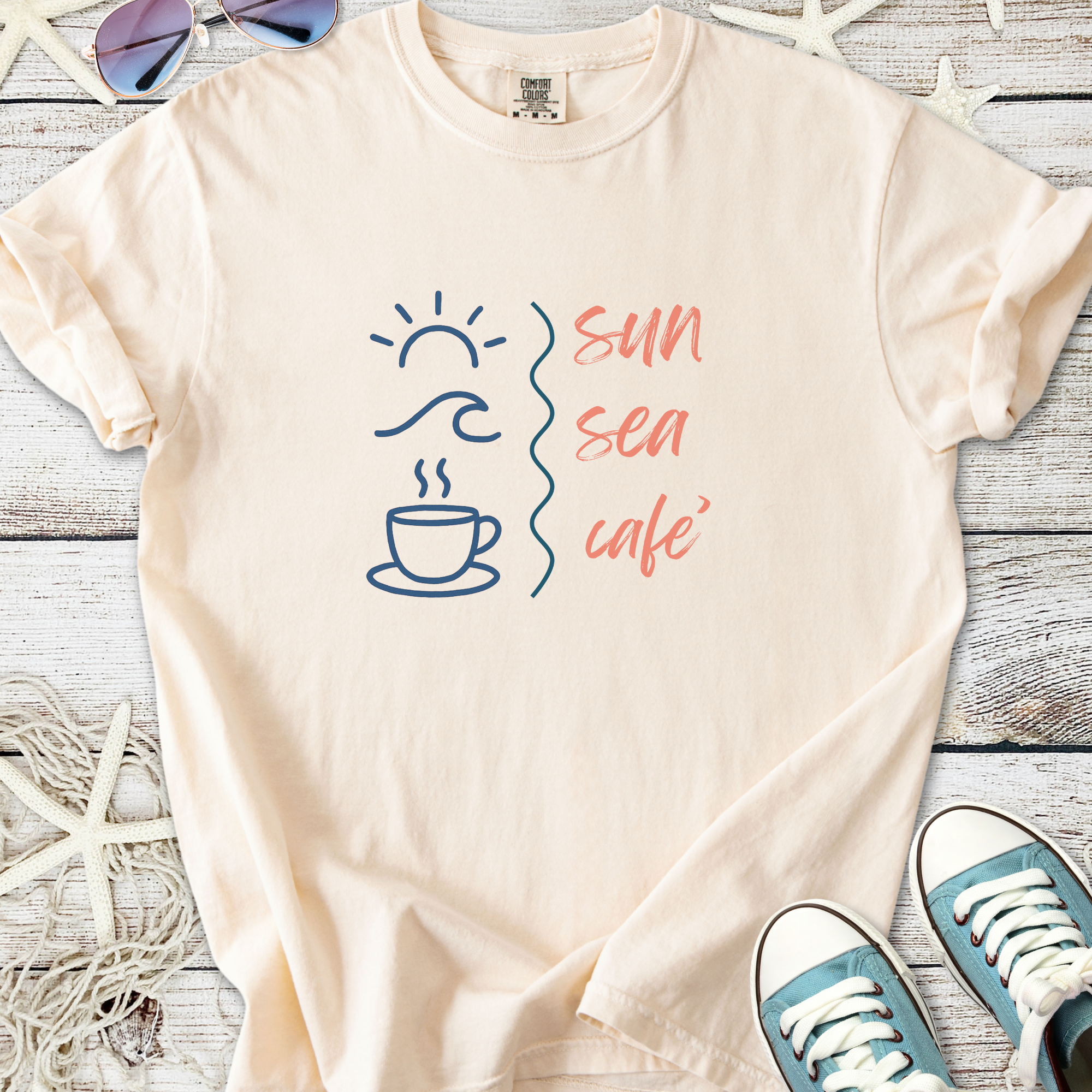 Light beige t-shirt with 'sun sea café' graphic, featuring coffee cup, sun, and wave designs.