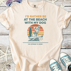 Light peach t-shirt with beach dog graphic, featuring a surfing dog in sunglasses and retro sunset design.