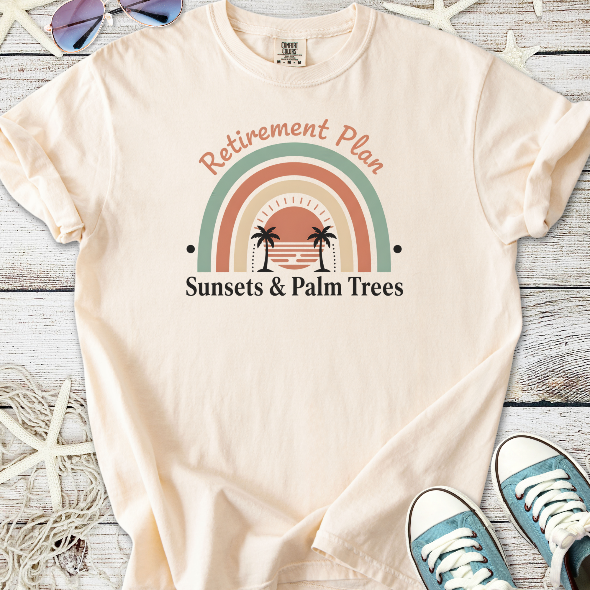 Cream cotton t-shirt with 'Retirement Plan: Sunsets & Palm Trees' graphic design.