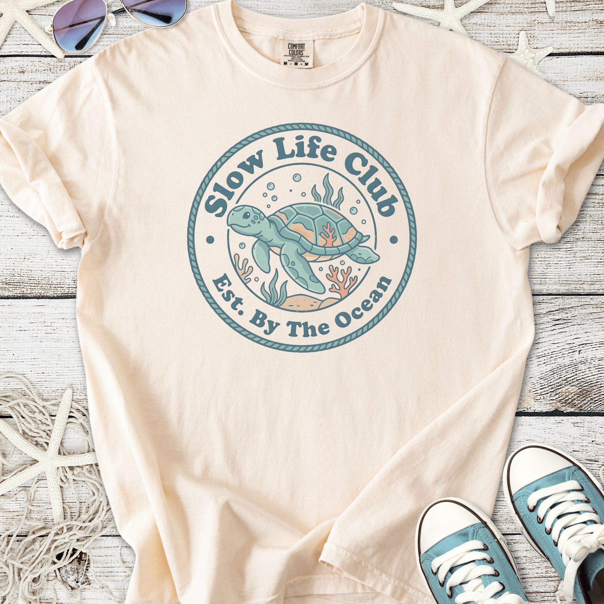 Beige cotton t-shirt featuring 'Slow Life Club' turtle graphic, ocean-themed design, perfect for beach lovers.