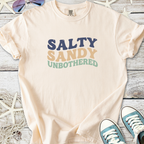 Cream t-shirt with 'Salty Sandy Unbothered' graphic, perfect for beach lovers and casual wear.