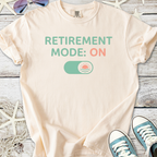 Cream t-shirt with 'RETIREMENT MODE: ON' graphic, perfect for casual wear or retirement celebrations.