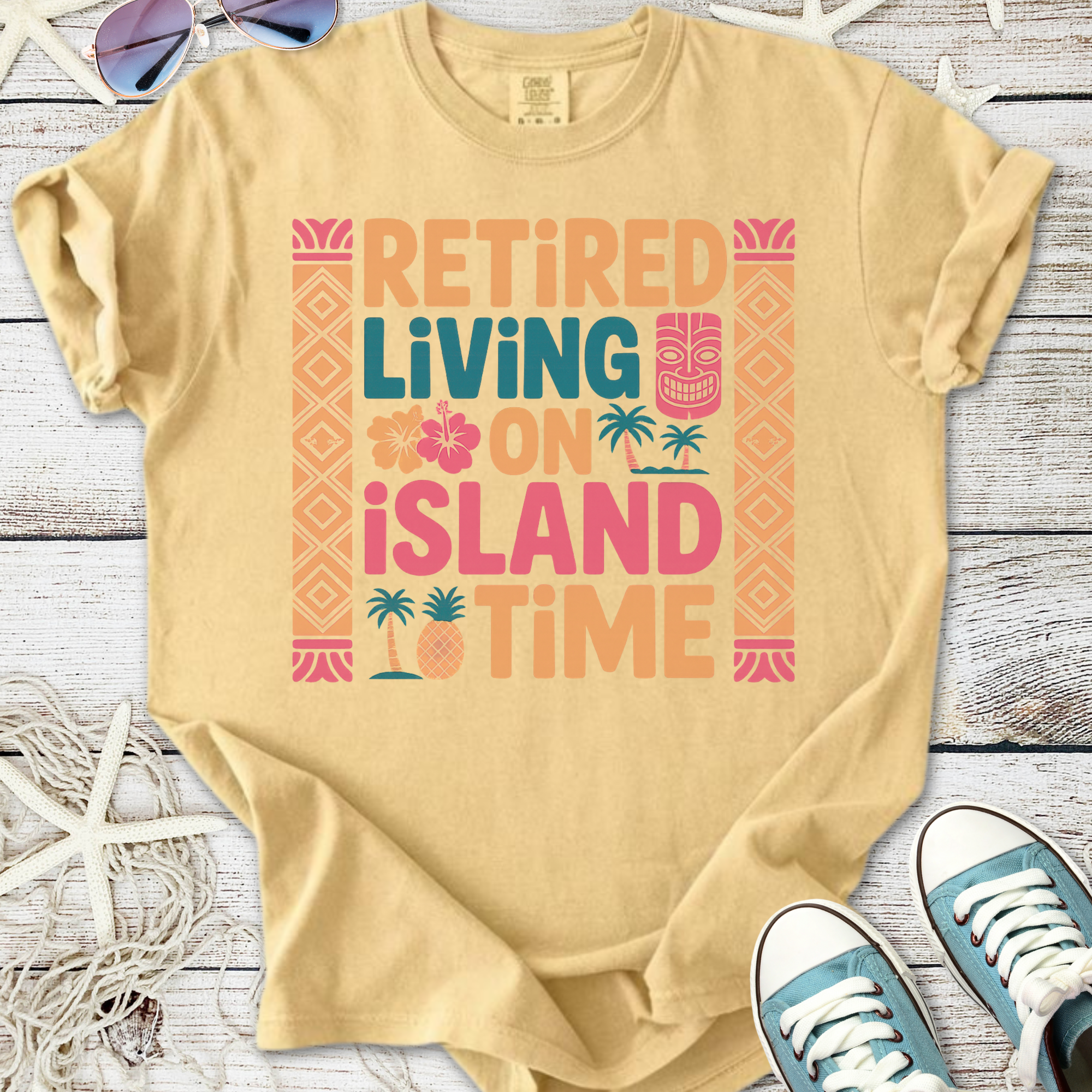 Beige graphic tee featuring 'Retired Living on Island Time' design with tropical elements.