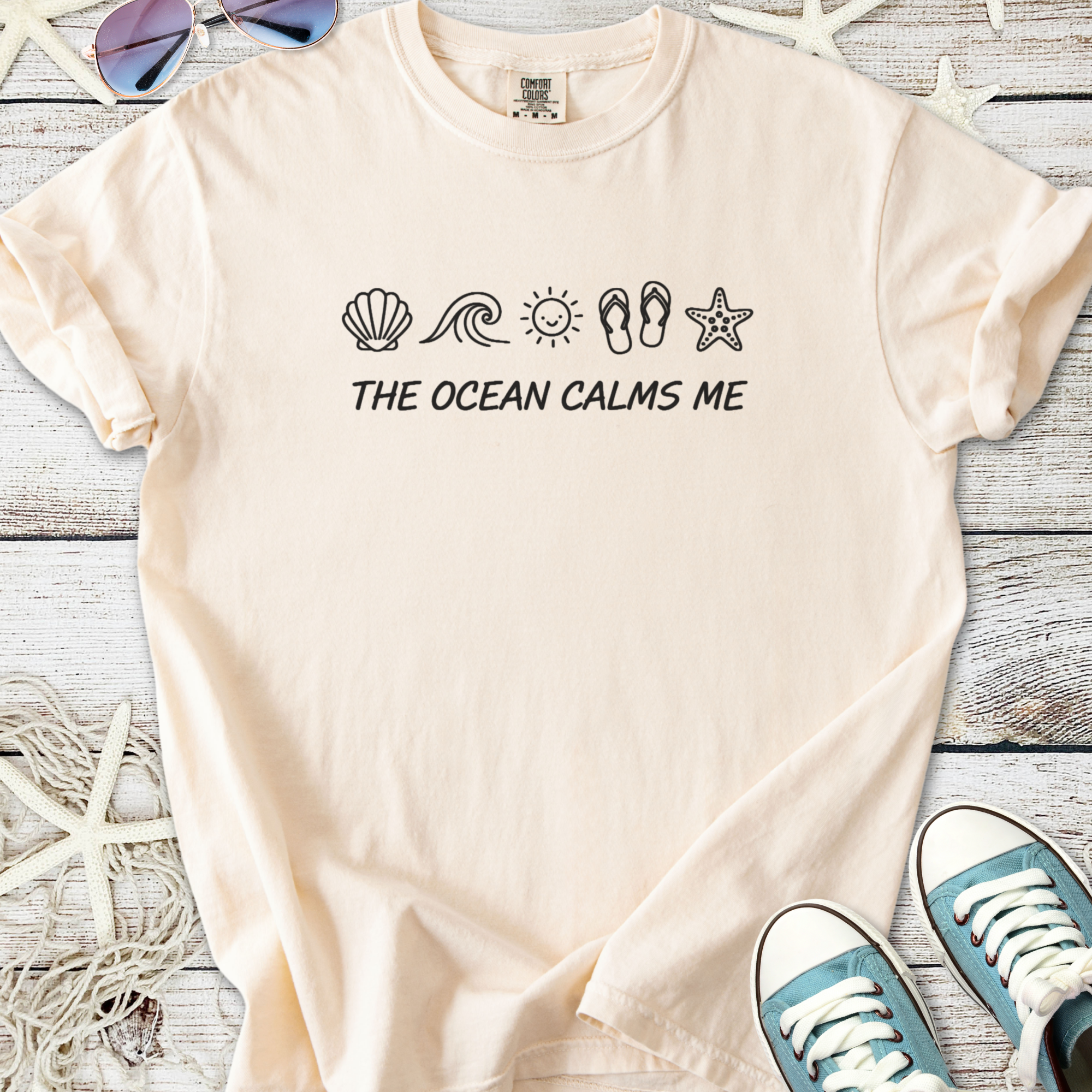 Beige cotton t-shirt with ocean-themed print and 'The Ocean Calms Me' slogan, perfect for beach lovers.