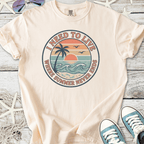 Men's beige t-shirt with 'I Need to Live' graphic, featuring a sunset and palm tree design.