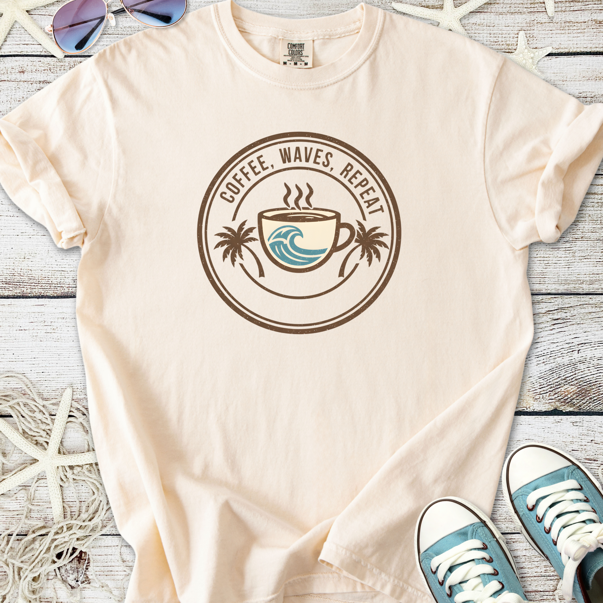 Beige unisex t-shirt with 'Coffee, Waves, Repeat' graphic, featuring a coffee cup and palm trees.