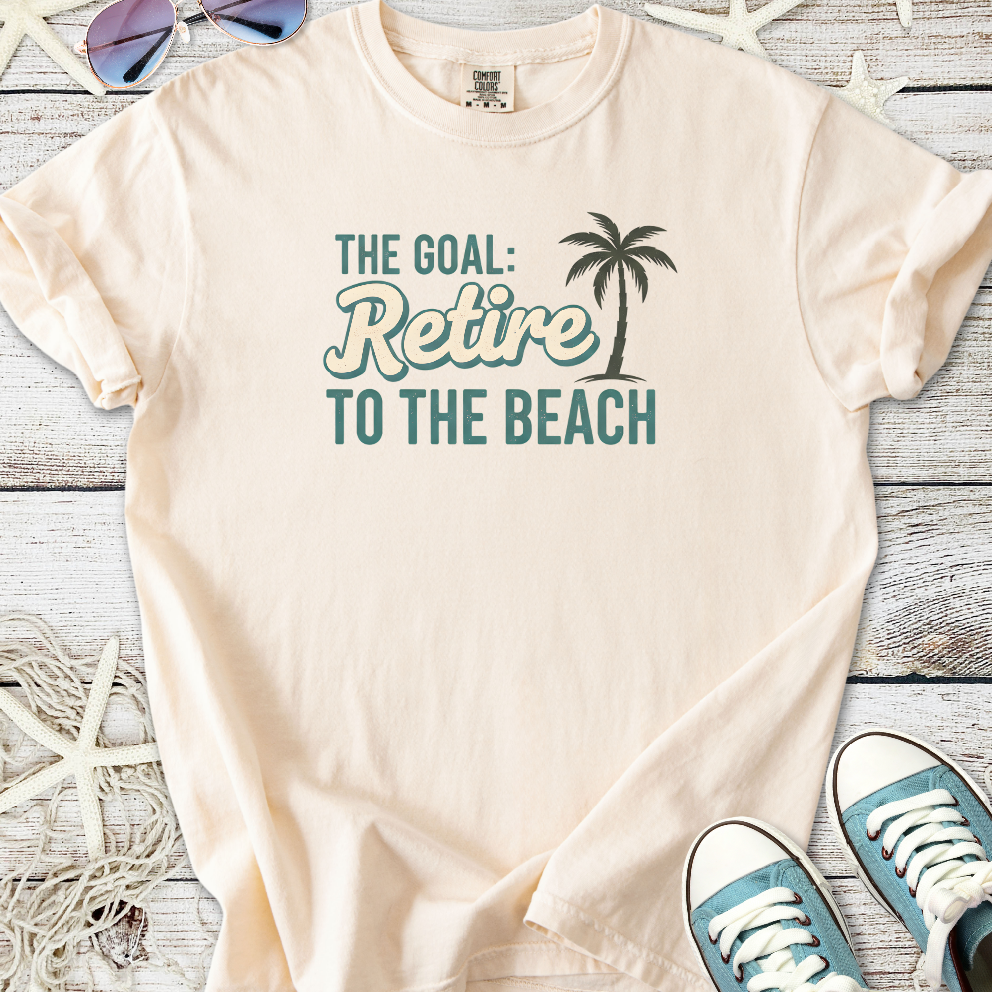 Light beige t-shirt featuring palm tree graphic and 'Retire to the Beach' quote for relaxed wear.