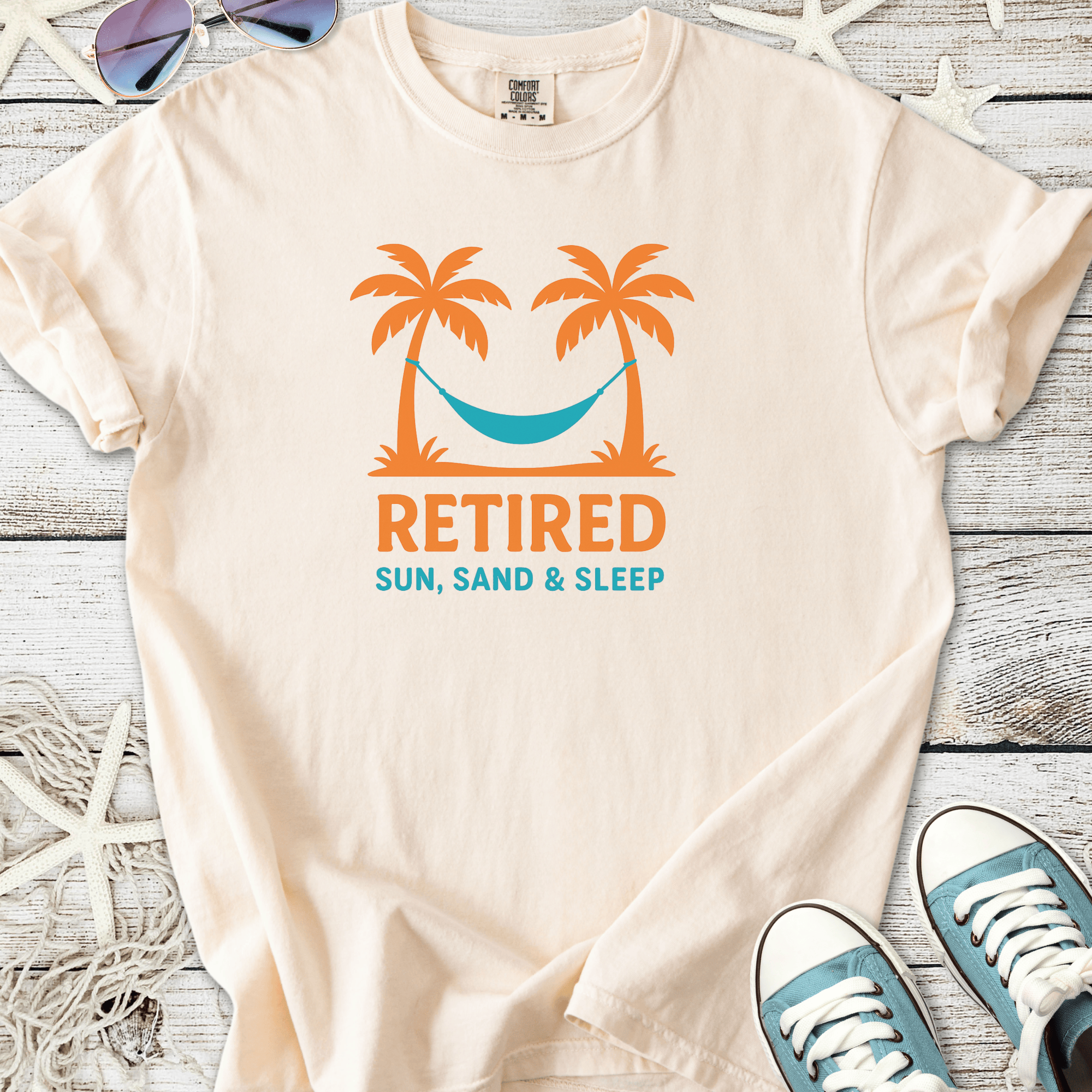 Cream retiree t-shirt with palm trees and hammock graphic, featuring 'Retired Sun, Sand & Sleep' text.
