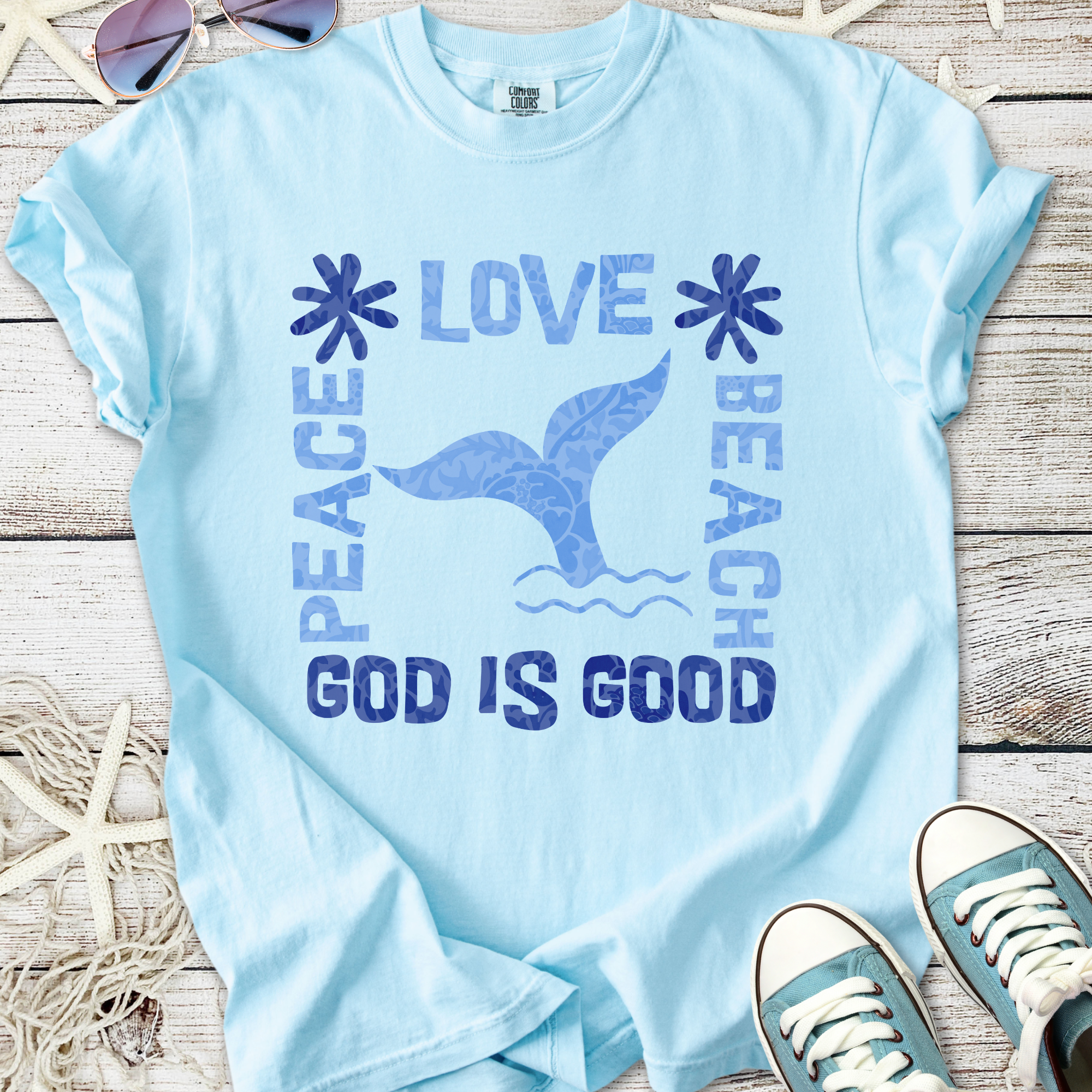 Light blue t-shirt featuring 'Peace Love Beach' design and mermaid tail graphic, perfect for summer vibes.