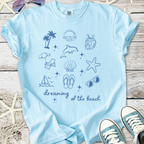 Light blue t-shirt featuring beach-themed graphics and the phrase 'dreaming of the beach'.